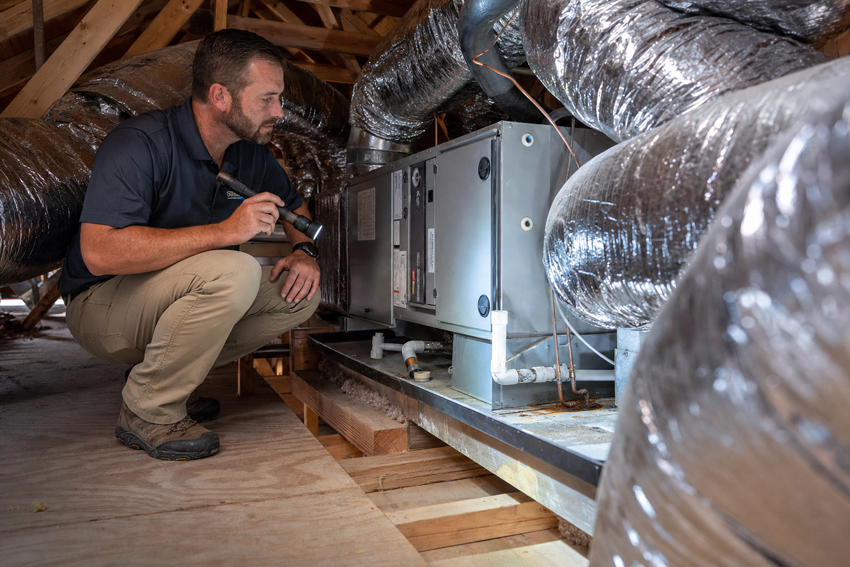 A home inspector checks an attic air handler, ducts, and condensate pan. The scene highlights common HVAC findings that can appear in inspection reports.